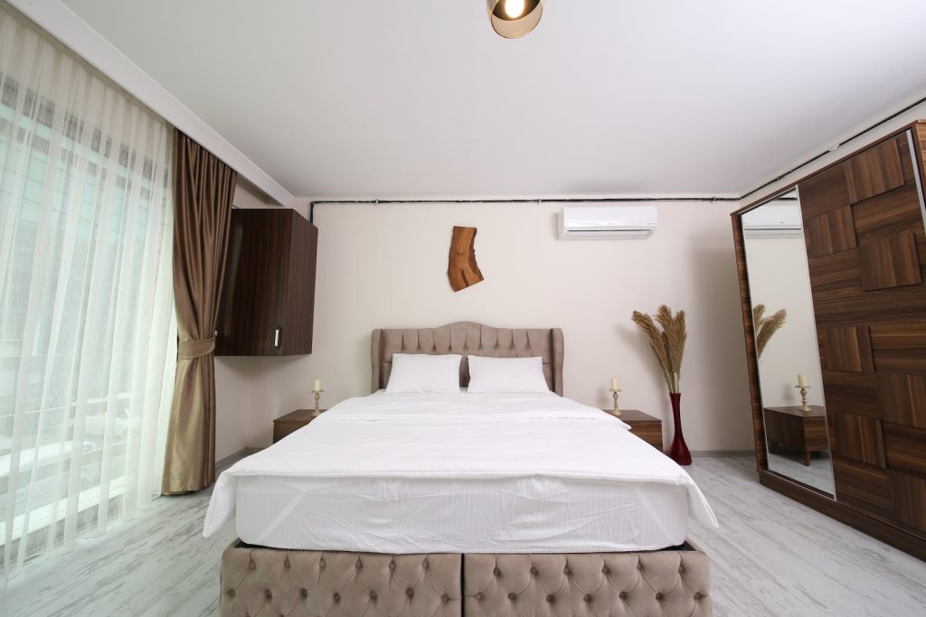White Bed Linen With Brown Bed Frame with ac unit in room